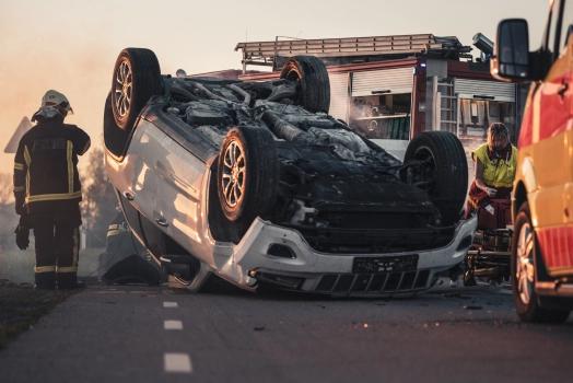 Burning Vehicle Lying on its Roof in the Middle of the Road after Collision.